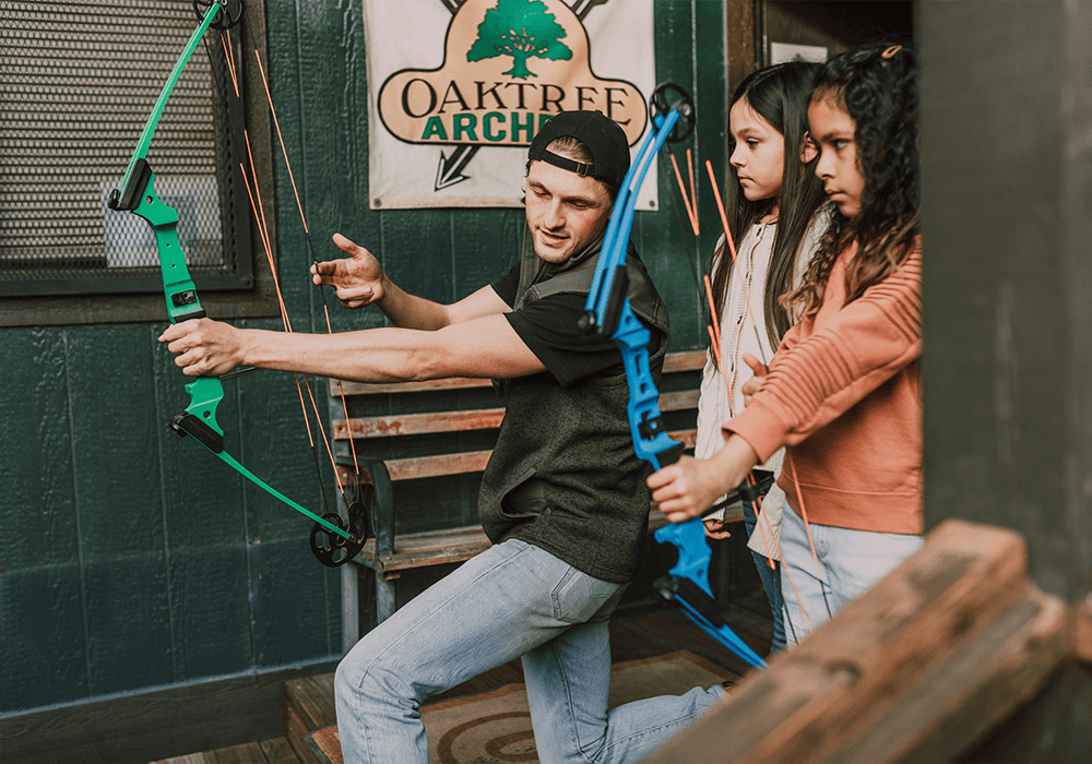 An instructor and two students practicing archery inside Oak Tree Archery Range.