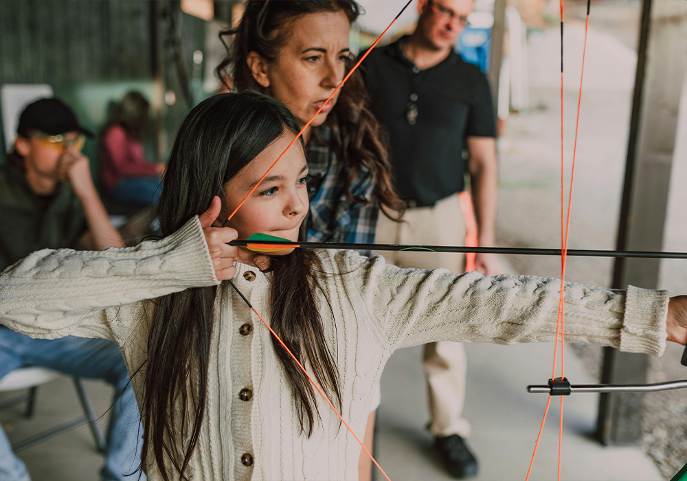 Young girl getting help with archery.