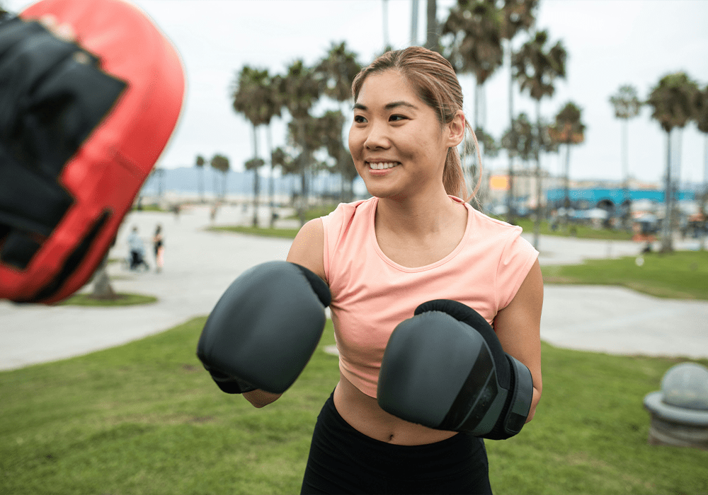 Girl smiling wearing boxing gloves engaged in training.